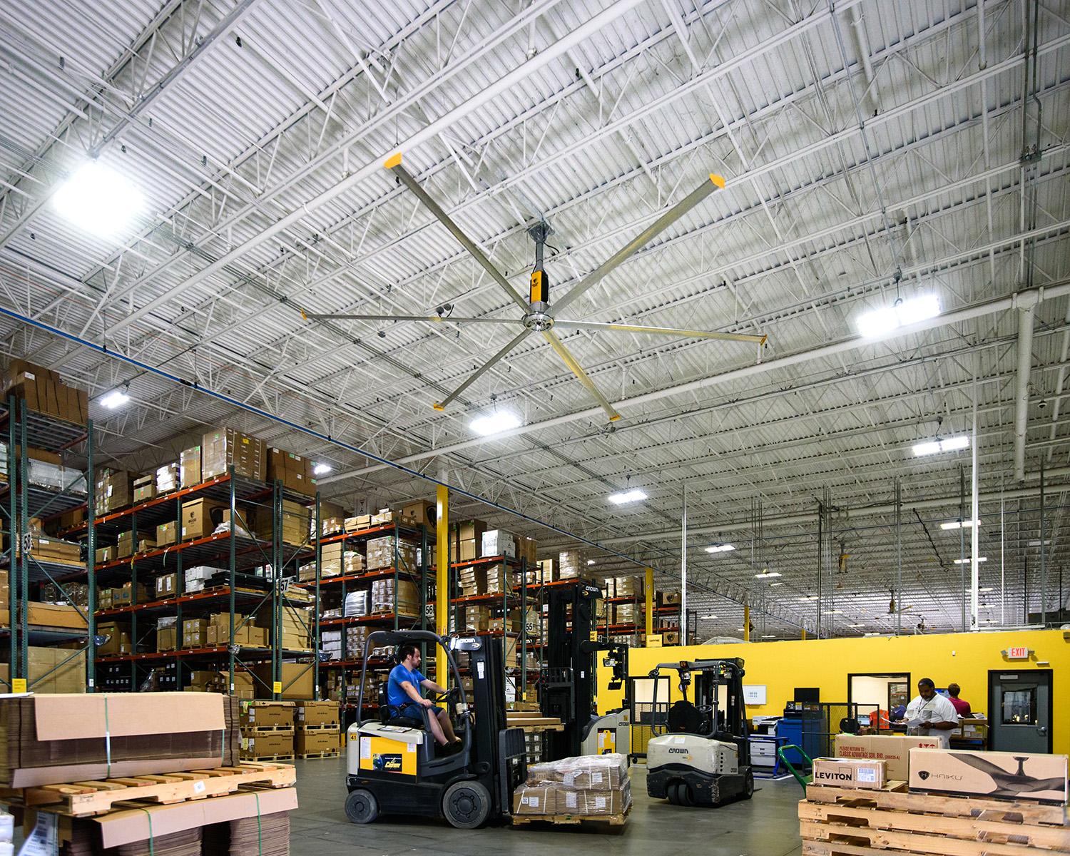 A spacious warehouse interior featuring a large ceiling fan for ventilation.
