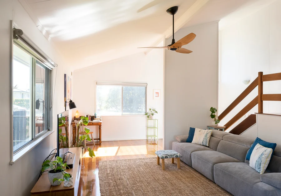Ceiling fan in a cozy living room with natural light and plants, featuring a modern, minimalistic design