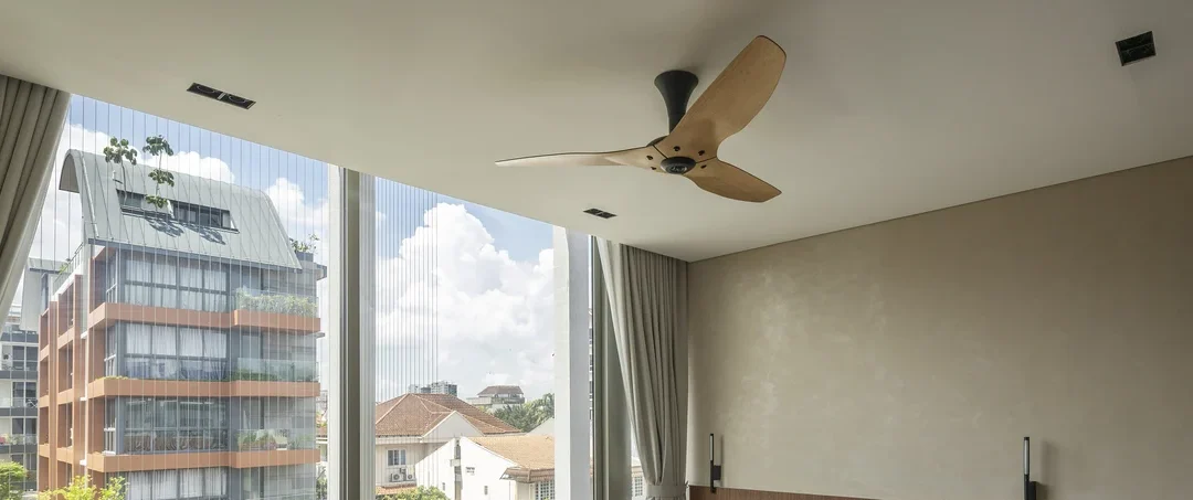 Wooden ceiling fan in a living room with large windows