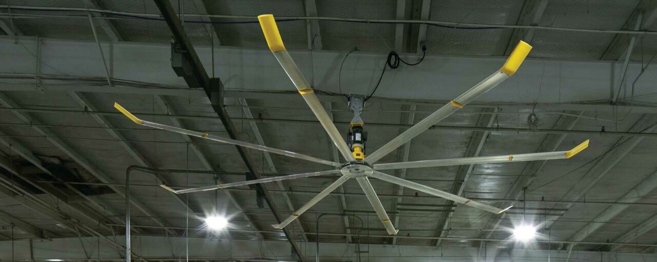 Inside an expansive warehouse, an HVLS fan by Big Ass Fans is expertly positioned to provide optimal airflow.