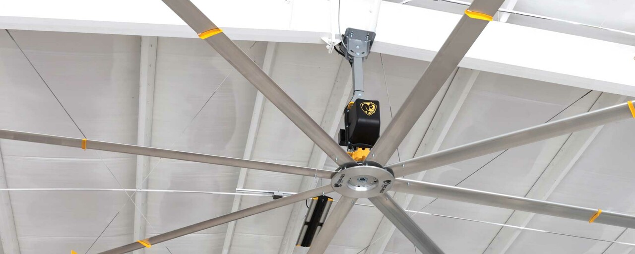 The view of a metal ceiling in a large warehouse or workspace with a high volume low speed fan by Big Ass Fans.