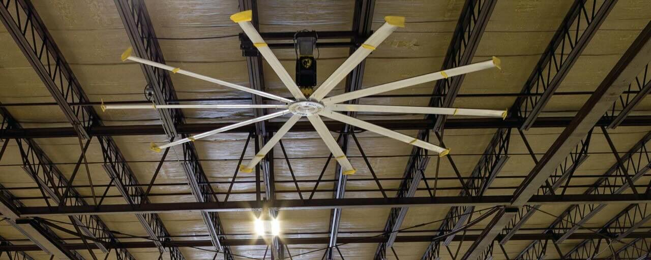 Looking up at a warehouse ceiling in a voluminous room with a large HVLS ceiling fan by Big Ass Fans providing optimal airflow.